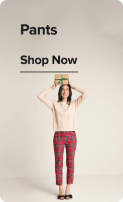 Sweaters. Shop now. A woman wearing a white sweater with a red and blue sweater dropped over her shoulders.