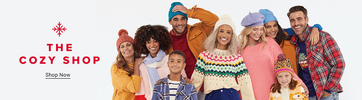 An image of a group of men, women and kids, all wearing cozy sweaters, flannel, toboggans and more. The Cozy Shop. Shop now.