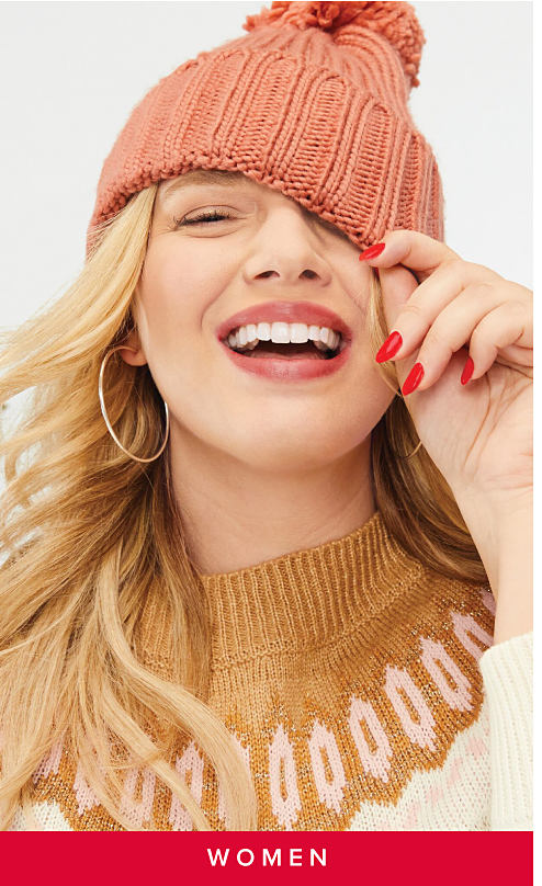 An image of a woman in a pink toboggan and a brown sweater. Shop women. 