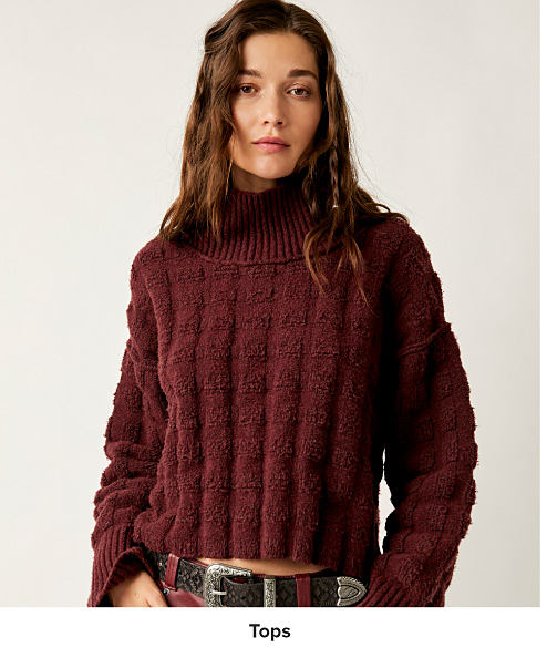 An image of a woman wearing a cropped sweater. Shop tops.