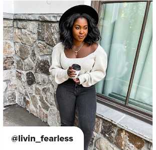 A woman in a black hat with dark grey denim, wearing a white shirt with puffy sleeves. At Livin underscore Fearless. 