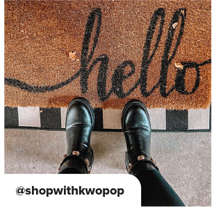 Black boots in front of a hello door mat. At Shop with Kwo Pop. 
