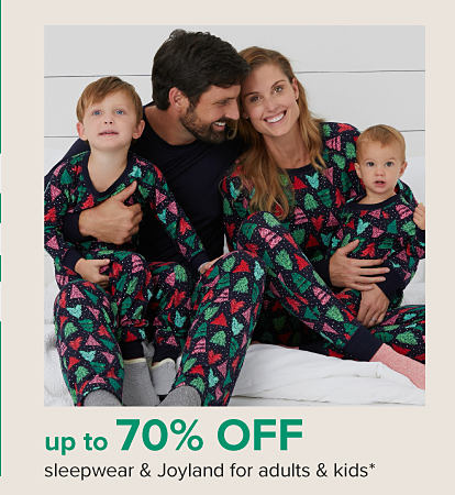 A picture of a family in matching Christmas pajamas. Up to 70% off sleepwear and Joyland for adults and kids. 