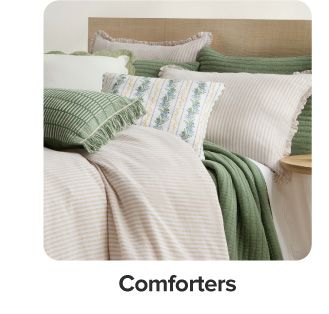 A bed with green and beige bedding. Shop comforters.