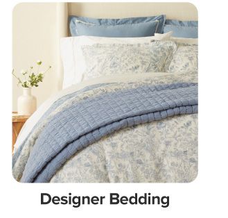 A bed with blue and white bedding. Shop designer bedding.