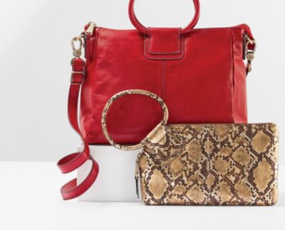 Image of a red handbag and a snakeskin wristlet. Bring on the style.