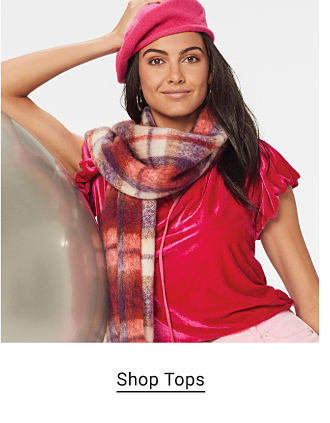 Woman wearing a red velvet shirt and plaid scarf. Shop tops.