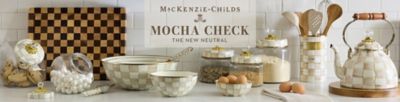 A variety of Mackenzie Childs products on a kitchen countertop. The Mackenzie Childs logo. Mocha check, the new neutral.