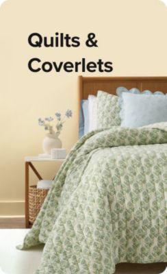 Shop quilts and coverlets. A bed with green bedding.